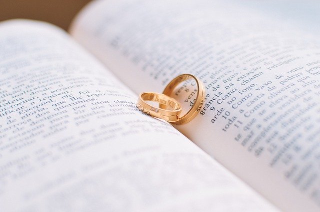 Two gold wedding bands sitting on an open book